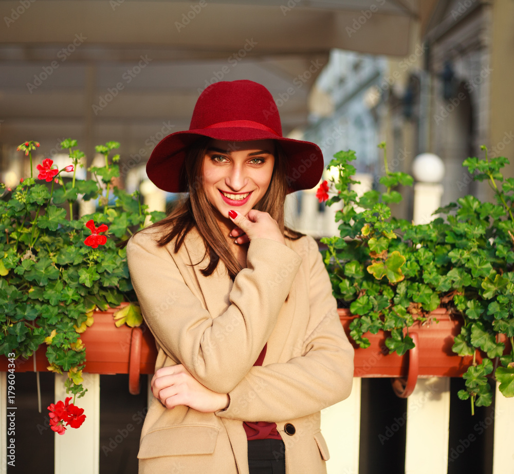 Cute girl in coat on street tourist town with flowers on sunset