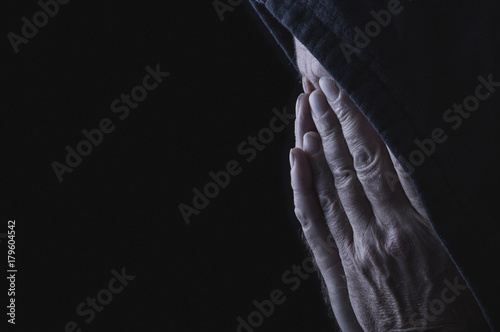 Concept despair, human hands covering the face of a elderly man in front of black background