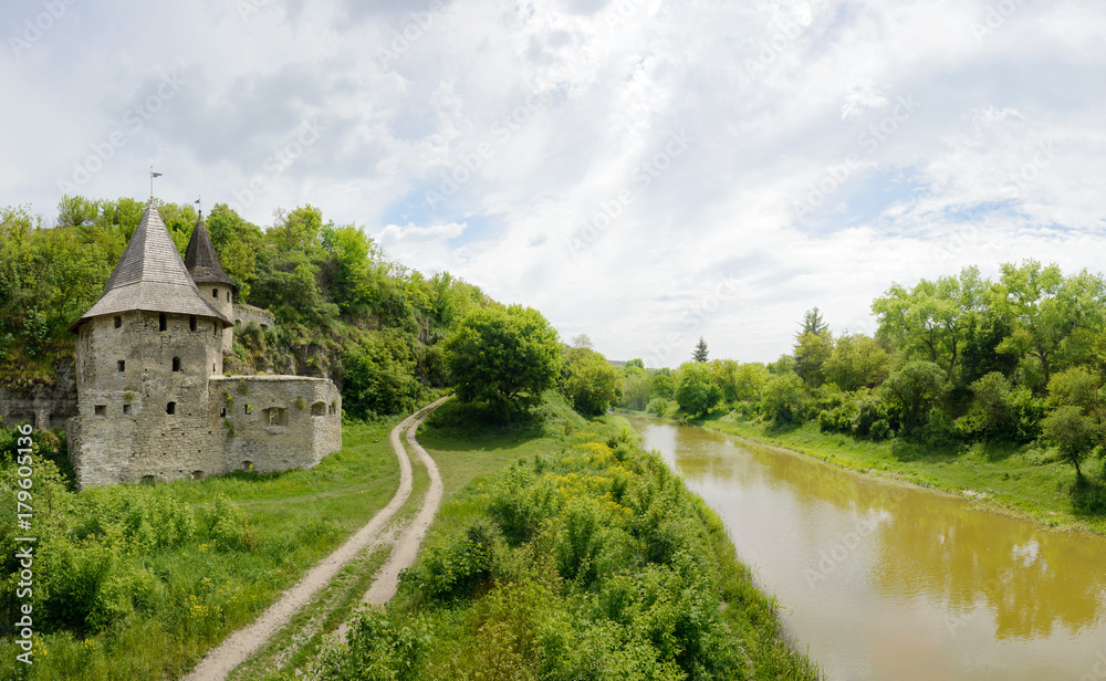 Old castle with road and river on cloudy sky background