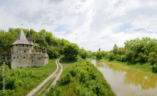 Old castle with road and river on cloudy sky background