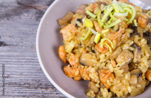 Risotto with mushrooms and chicken decorated with leek on a wooden background