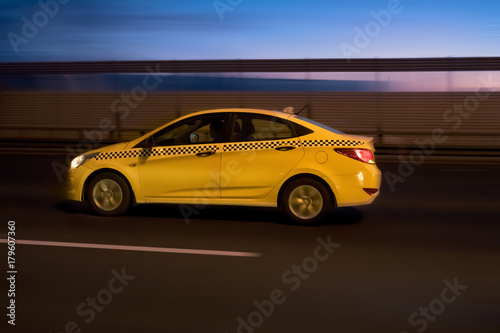 Moscow taxi quickly drives around the city street at night with a blurry background. Motion blur