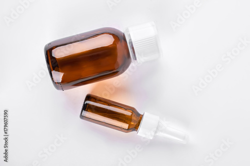 Brown glass bottles with medicine. Amber bottles of big and medium size with medical liquid on white background  top view. Antipyretic syrup over white.