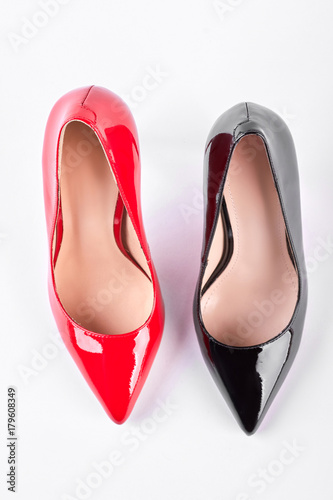 Red and black heels, top view. Fashionable lacquered high heels over white background. Female trendy shoes.