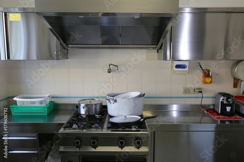 industrial kitchen with stainless steel cookers and suction hood