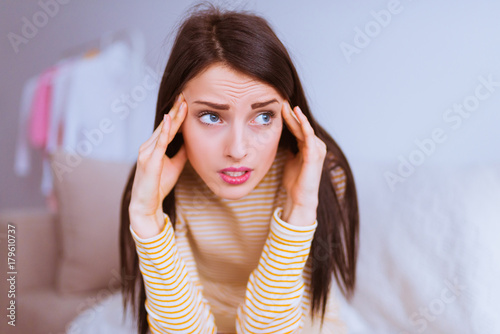 Lovely concerned woman sits and keeps of hands her head at home