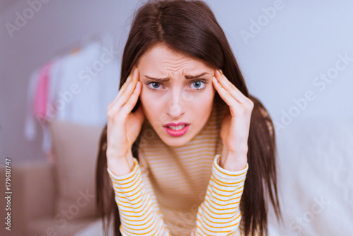 Attractive concerned woman sits and keeps of hands her head at home alone