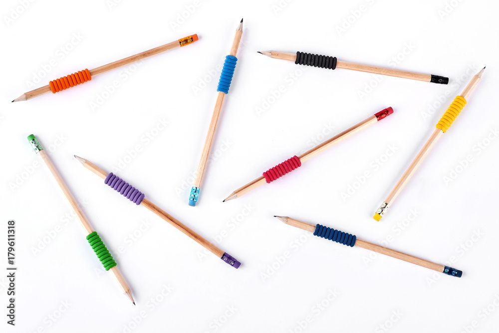 Background of different pencils. Simple pencils with colorful elastic bands chaotically placing on white background, top view.