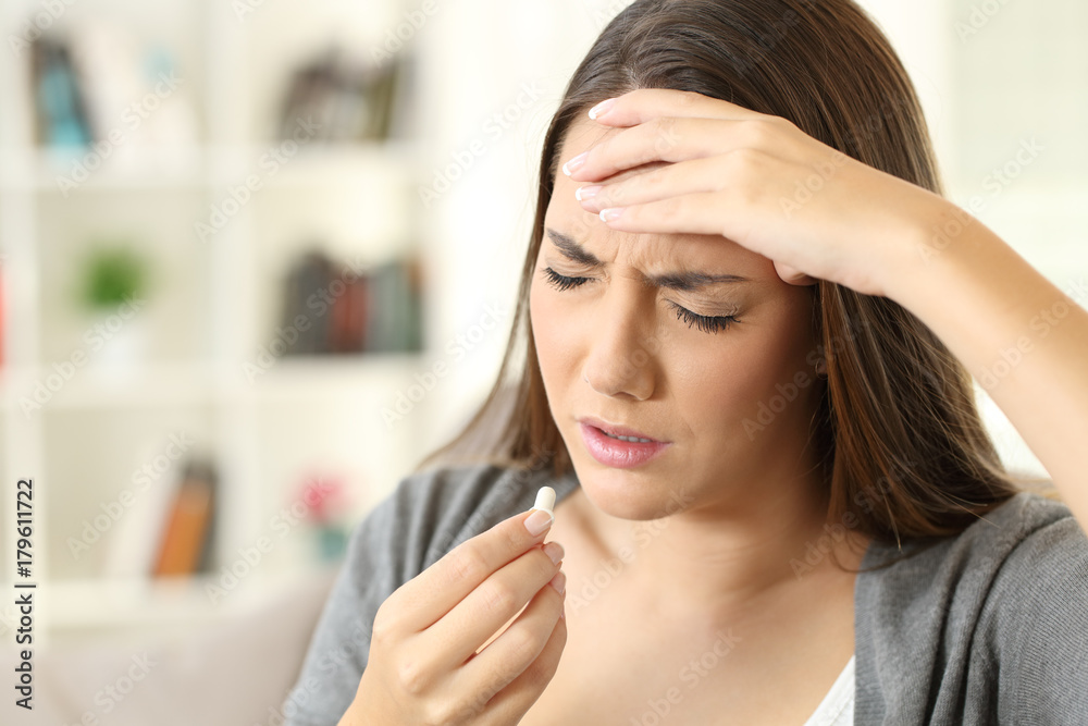Ill woman suffering headache taking a pill Ill woman suffering headache taking a pill