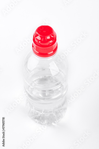 Mineral bottle of water, white background. Plastic bottle of water with red cap isolated on white background. Sport and healthy lifestyle concept. photo