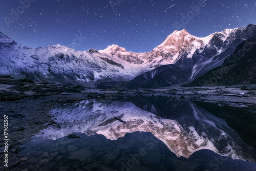 Amazing night scene with himalayan mountains and mountain lake at starry night in Nepal. Landscape with high rocks with snowy peak and sky with stars reflected in water. Beautiful Manaslu, Himalayas © den-belitsky