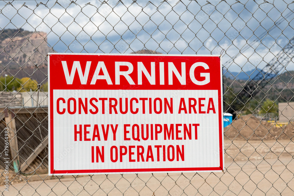 Warning construction area sign hanging on a chain link fence Stock