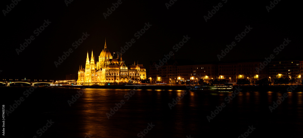 Panoramic view of Hungarian Parliament reflecting in Danube river. Night cityscape of Budapest