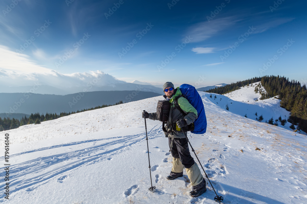 Hiker is posing to the camera in winter mountains