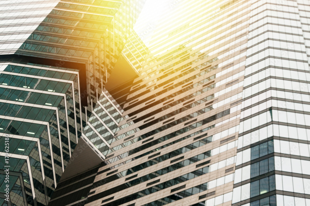 Obraz premium Modern glass building business center. Skyscraper in the city. The sun's rays are reflected in the glass surface of the building. Bottom view.