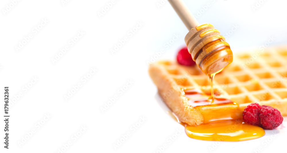 Belgian waffles with honey and berries closeup over white background Belgian waffles with honey and berries closeup over white background