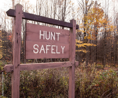 A "HUNT SAFELY" sign in the woods in the fall