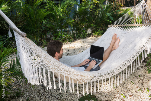 Homme et ordinateur portable dans un hamac photo