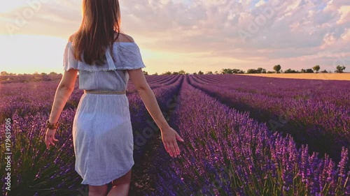 Happy Woman Enjoying Life in Lavender Field at Sunset. SLOW MOTION 120 FPS STABILIZED SHOT. Joyful girl walking in endless blooming lavender fields. Plateau du Valensole, Provence, France. Lens Flare