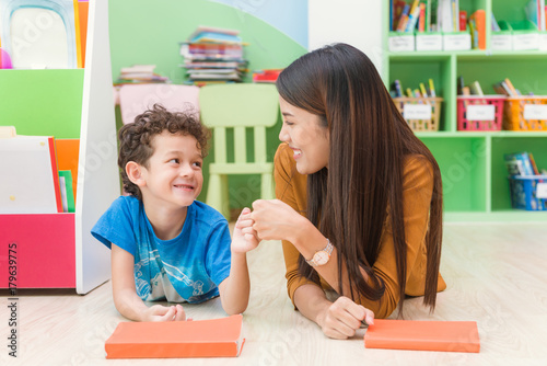 Young asian woman teacher teaching american kid in kindergarten classroom with happiness and relaxation. Education, elementary school, learning and people concept - teacher help school kids classroom. photo