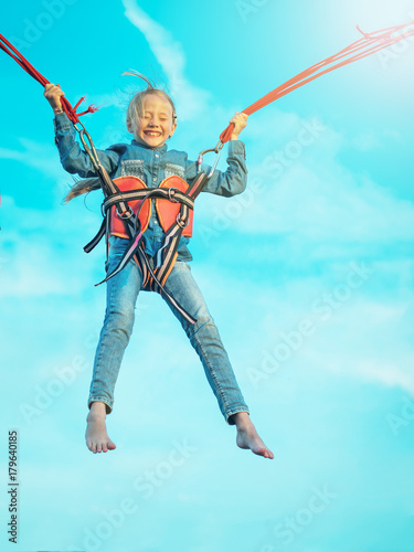 Girl in denim soars upward bound straps.