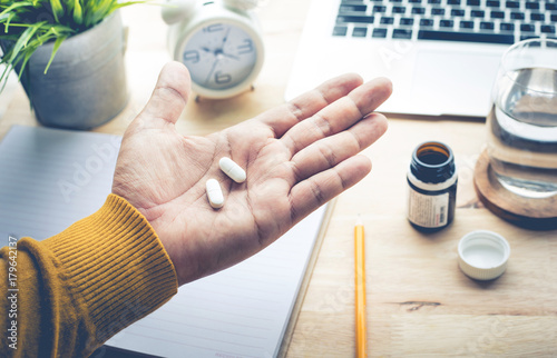Male eating medicine,pill (vitamin) on work in morning.healthy lifestyle concepts