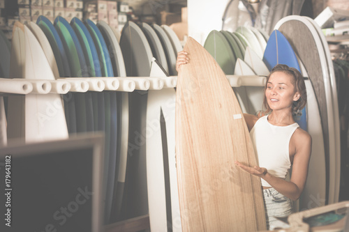 Portrait of smiling woman with board for surfing in the shop © JackF