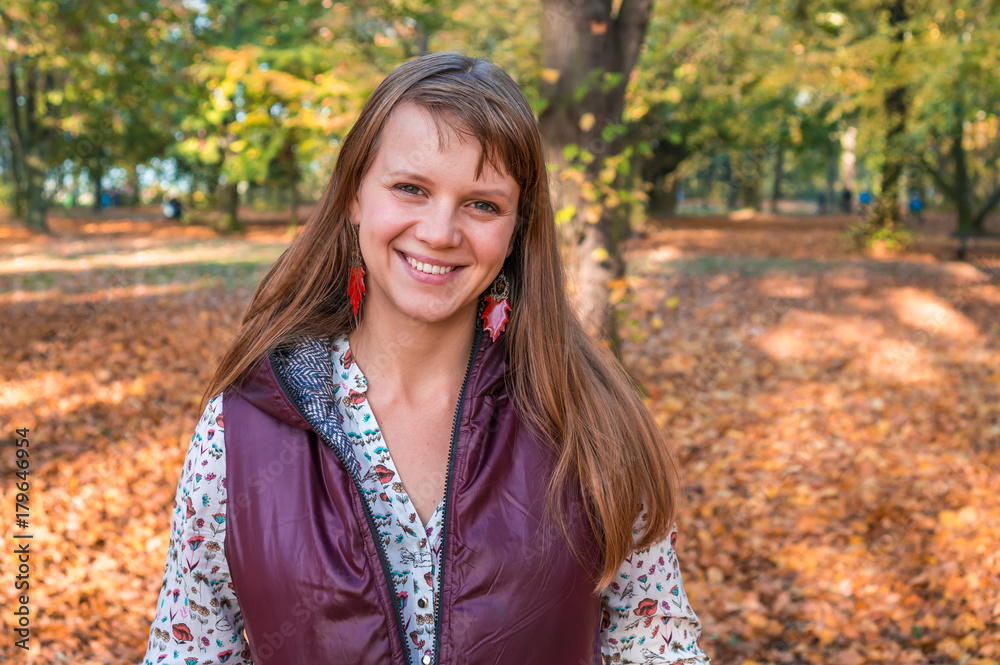 Fototapeta premium Smiling woman in park on sunny autumn day