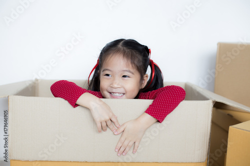 Asian Girl playing in the box at home. Kid sitting inside Box with Attractive smiling.