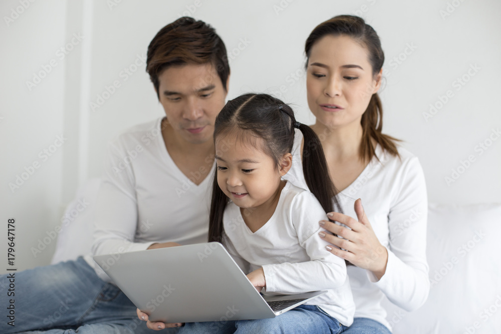 Attractive Little Girl using Laptop with Mom and Dad Together. Girl learning to use Laptop. Happy Family Concept. Attractive Little Girl using Laptop with Mom and Dad Together. Girl learning to use Laptop. Happy Family Concept.