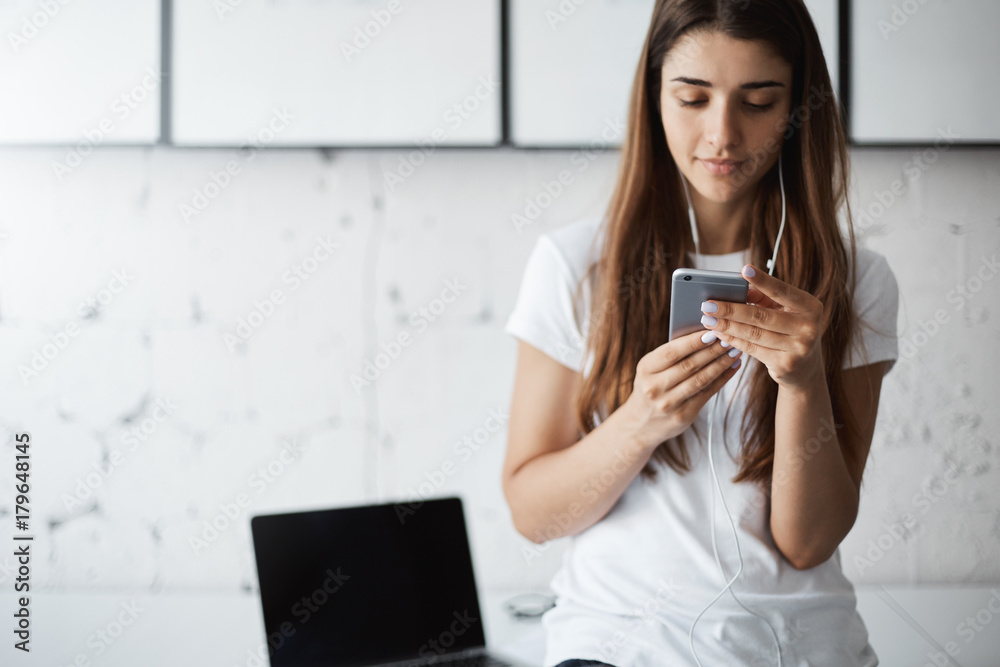 Beautiful nice young woman using smart phone to test her new application before publishing. Concentrated on her work. Beautiful nice young woman using smart phone to test her new application before publishing. Concentrated on her work.