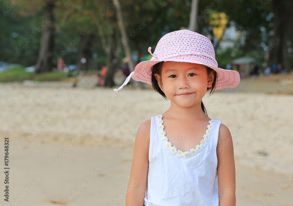 Portrait of cute little asian girl wear straw hat on the beach with looking at camera.