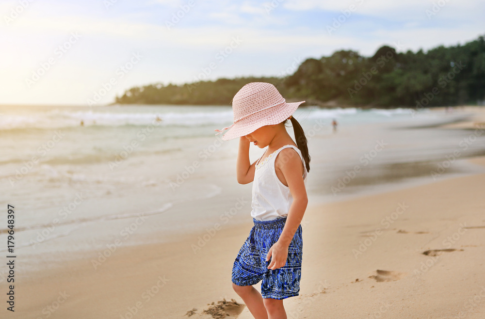 Portrait of cute little asian girl wear straw hat on the beach.