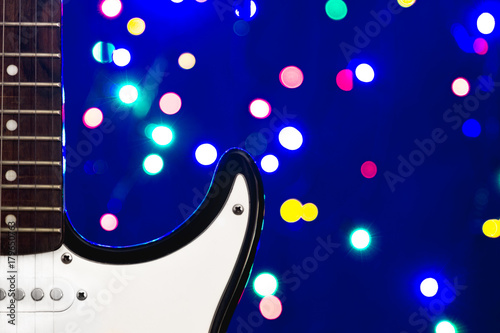 A part of white electric guitar with New Year or Christmass garlands on a blue background. Celebrating atmosphere.