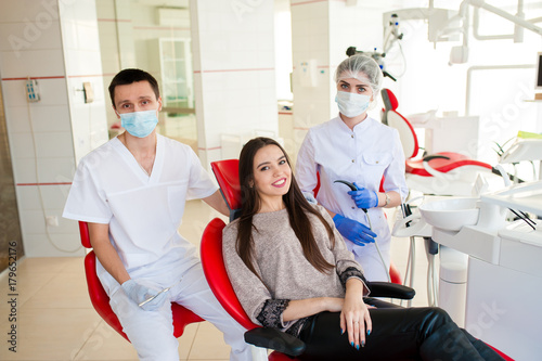 A dentist with an assistant  heals teeth to a beautiful girl.