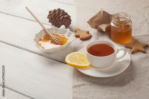 Composition of black tea with lemon, honey and cookies on a white background, copy space