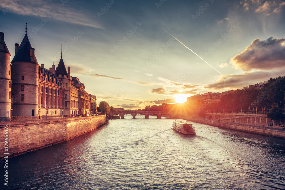 Fototapeta premium Piękna linia horyzontu Paryż, Francja, z Conciergerie, Pont Neuf i rejs łodzią przy zmierzchem. Kolorowe tło podróży. Romantyczny pejzaż.