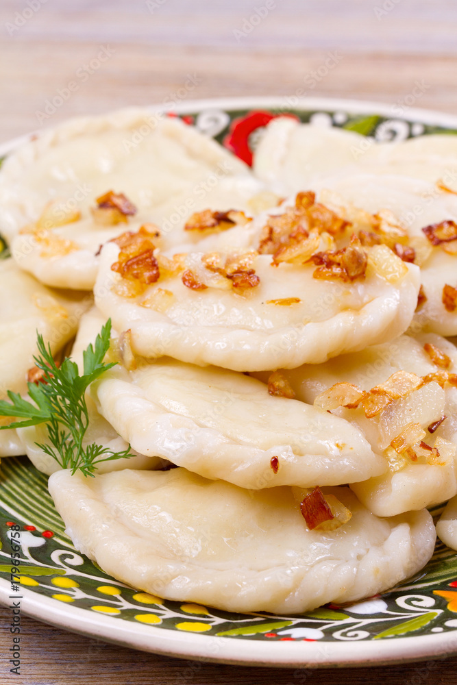 Dumplings, filled with potato and served with salty caramelized onion. Varenyky, vareniki, pierogi, pyrohy - popular dish in East Europe. View from above, vertical Dumplings, filled with potato and served with salty caramelized onion. Varenyky, vareniki, pierogi, pyrohy - popular dish in East Europe. View from above, vertical