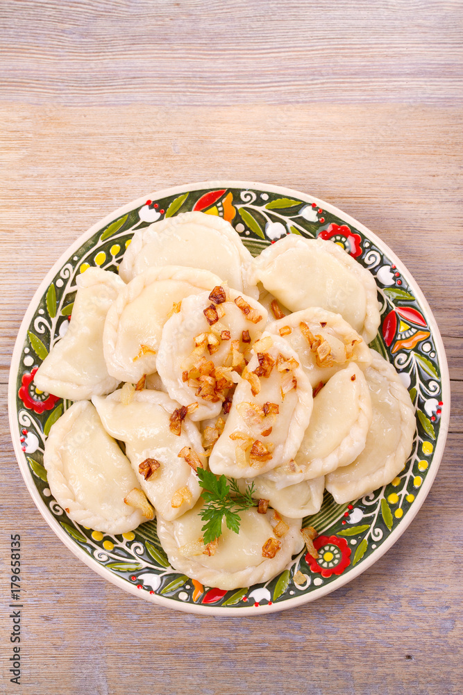 Dumplings, filled with potato and served with salty caramelized onion. Varenyky, vareniki, pierogi, pyrohy - popular dish in East Europe. View from above, top studio shot, vertical Dumplings, filled with potato and served with salty caramelized onion. Varenyky, vareniki, pierogi, pyrohy - popular dish in East Europe. View from above, top studio shot, vertical