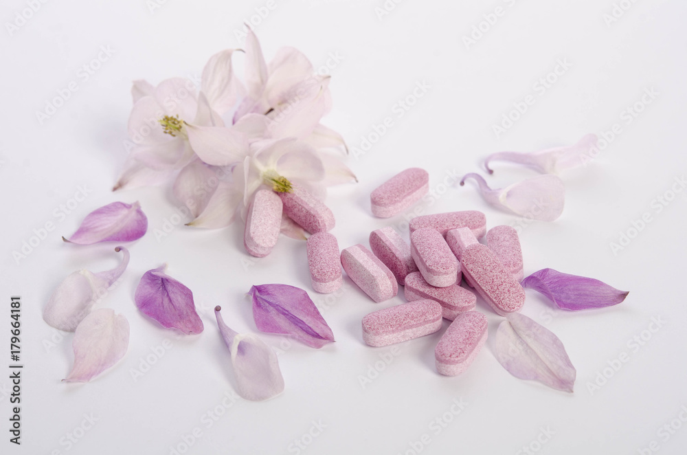 Alternative medicine tablets with flowers and petals on table Alternative medicine tablets with flowers and petals on table