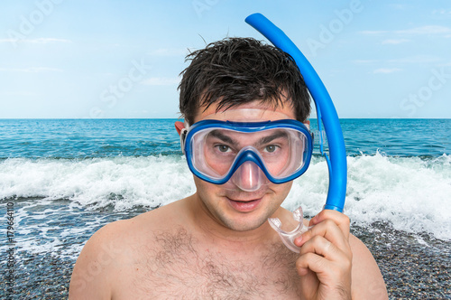 Man with snorkeling mask for diving stands near the sea