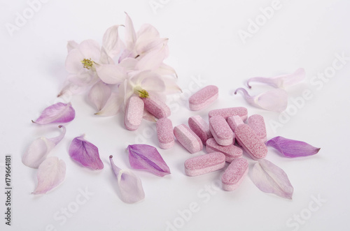 Alternative medicine tablets with flowers and petals on table