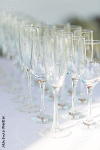 Empty champagne glasses in a row on white tablecloth.