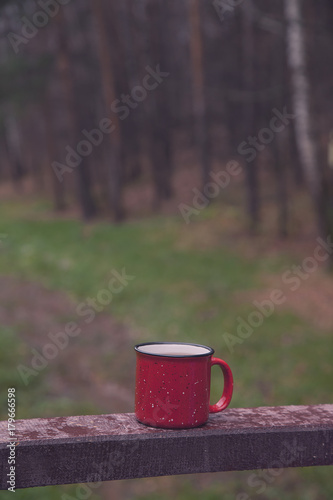 Red Cup with a drink on the wooden bridge in the morning forest