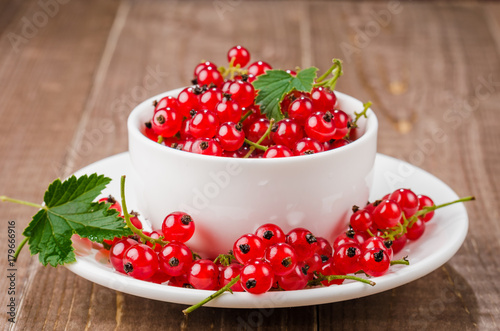 white cup full of red currant/white cup full of red currant. Selective focus