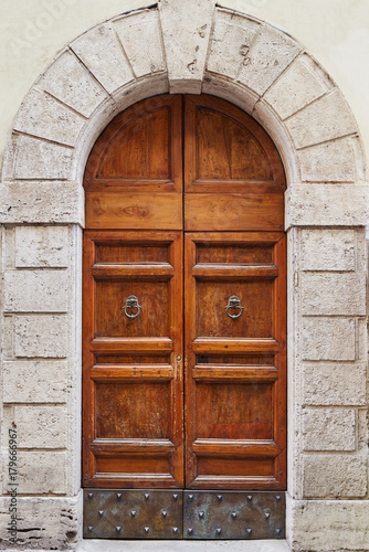 Old wooden brown door in a gray stone wall Rome, Italy
