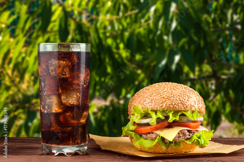 Delicious cheeseburger with salad ingredients on a grilled beef patty on a rustic wooden table with copyspace