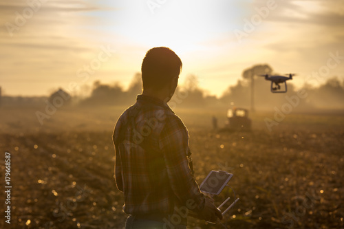 Farmer navigating drone above farmland