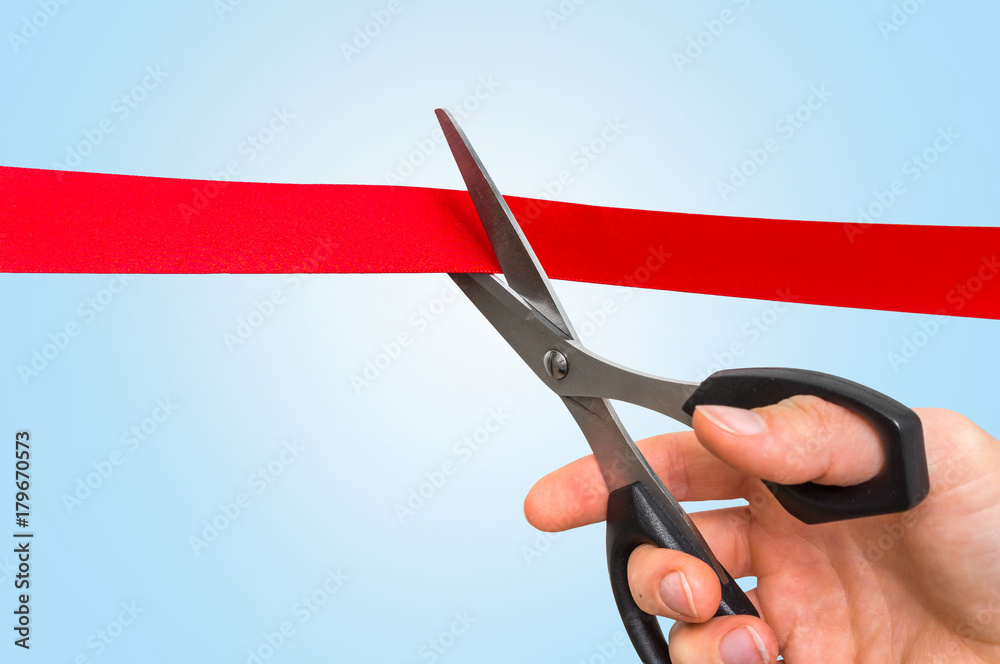 Hand with scissors cutting red ribbon - opening ceremony Hand with scissors cutting red ribbon - opening ceremony