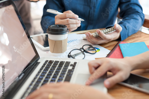 Young worker writing on notebbok while working with colleague